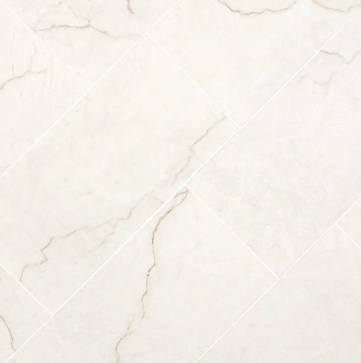 Brighton Gold 12X24 - Gallery – Flooring Office White marble tiles with subtle gray veining arranged diagonally with light grout lines providing a diamond pattern edge.